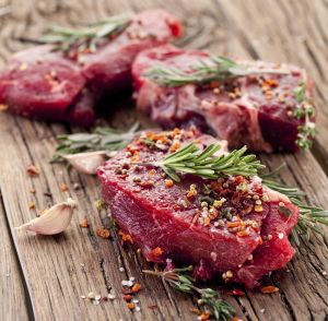 Raw beef steak on a dark wooden table.