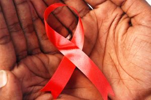 Top angle shot of the human hand holding a red ribbon, the AIDS symbol