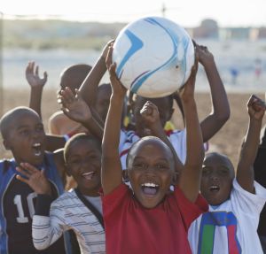 Boys playing soccer together in dirt field