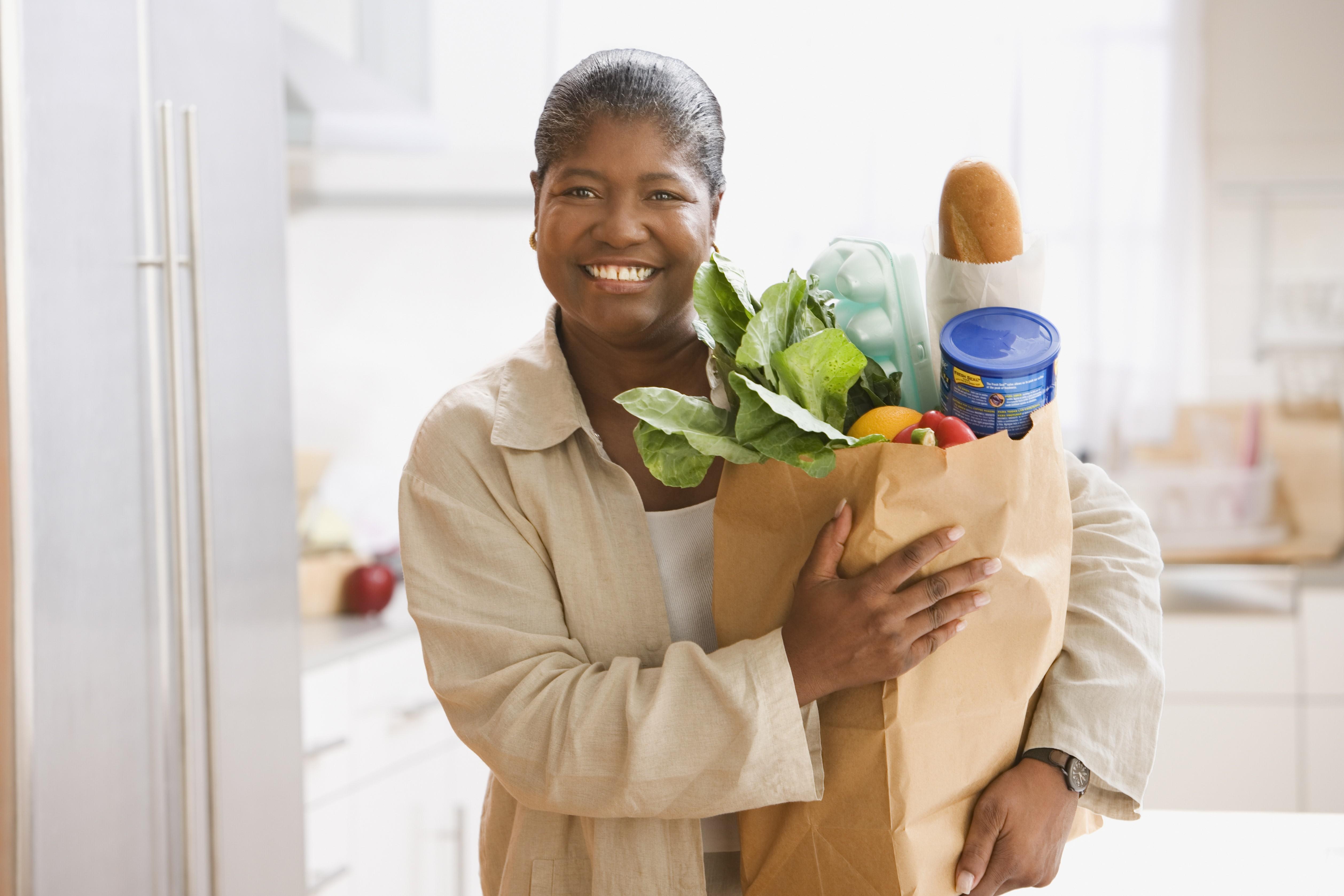 Middle-aged African woman holding a bag of groceries