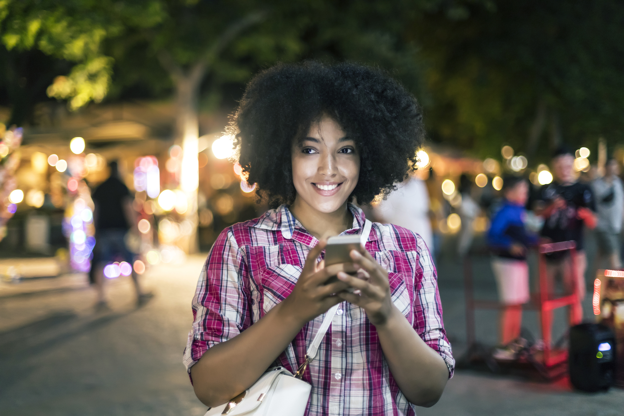 Smiling woman using smart phone on street at night