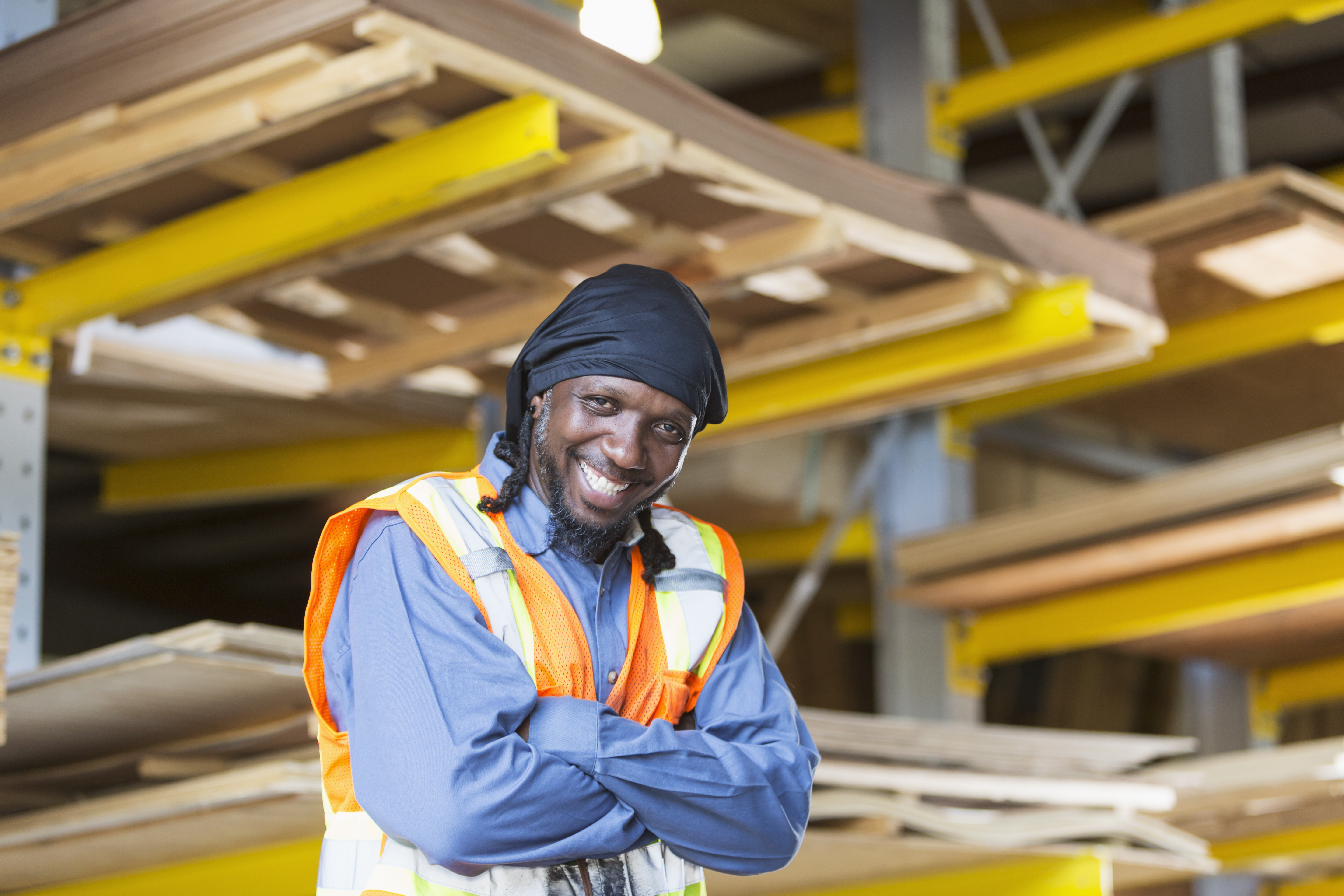 Black man working in warehouse wearing safety vest