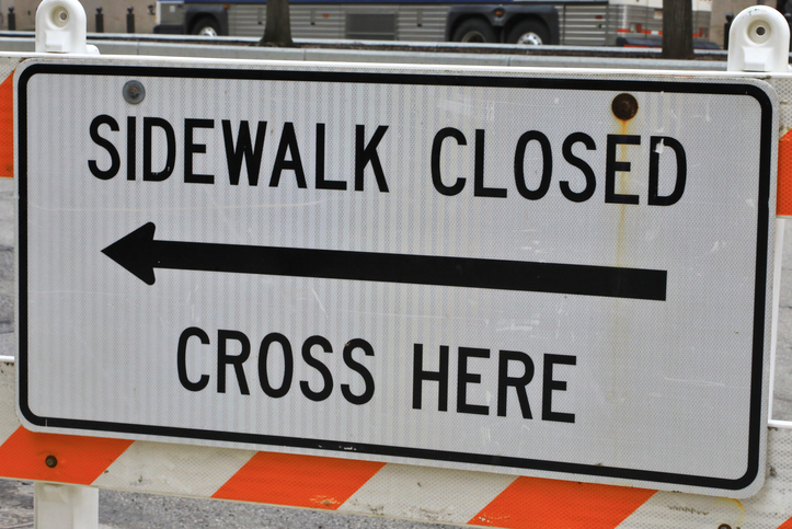Temporary barrier and sign notifying of a closed sidewalk ahead