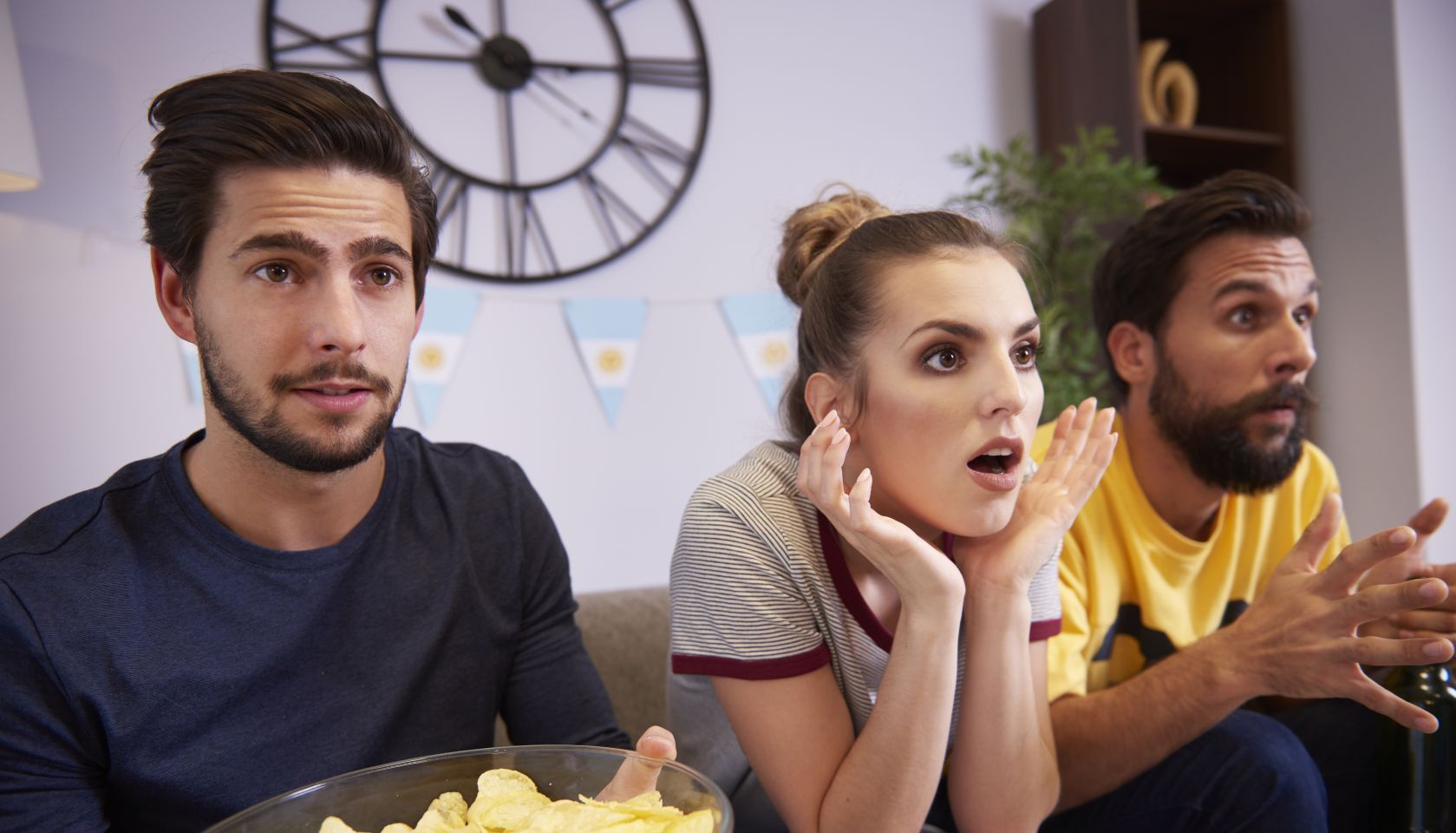 Excited friends sitting on the sofa watching Tv