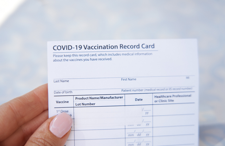 Woman holding covid-19 vaccination record card outdoors