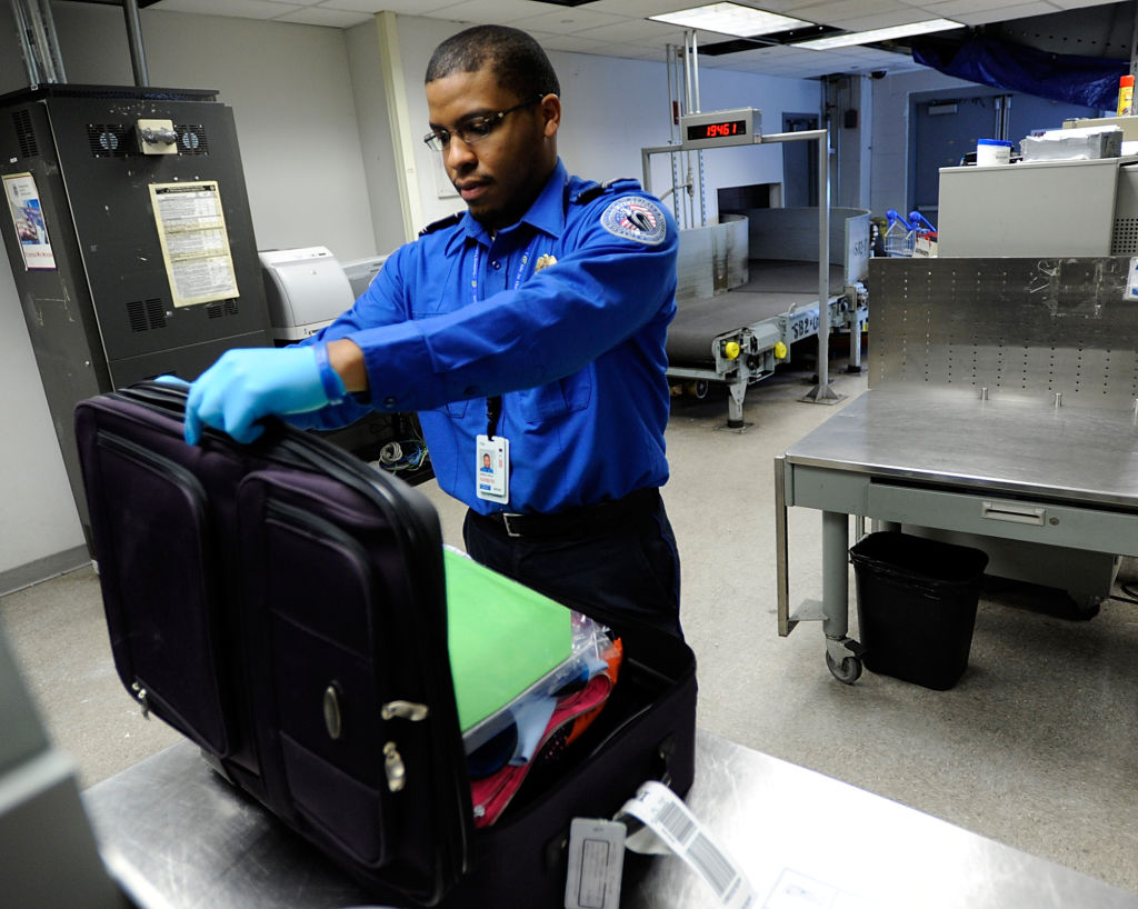 (032610, Boston, MA) Transportation Security Administration lead officer (most of the inspectors have this title) Ian Abreau-Riley inspects a bag inside one of the TSA's bag inspection areas at Logan International Airport on Friday, March 26, 2010. S