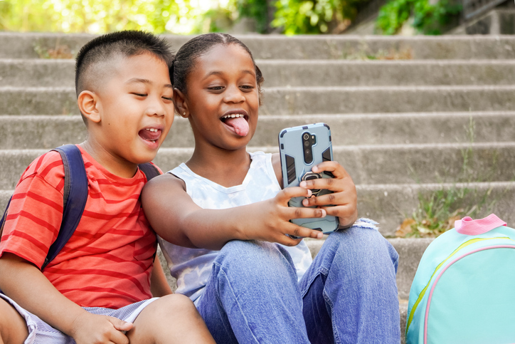 Happy multiethnic children taking selfie stiking out the tongue