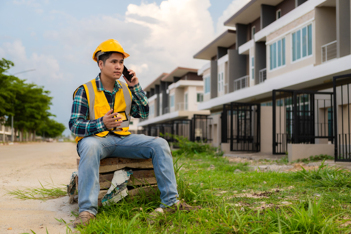 Young Asian engineer is inspecting work wearing a yellow hard hat at a construction site and about building a structure at work.