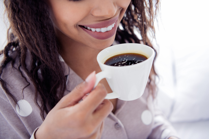 Young woman enjoying a morning coffee in comfortable sleepwear with a joyful smile