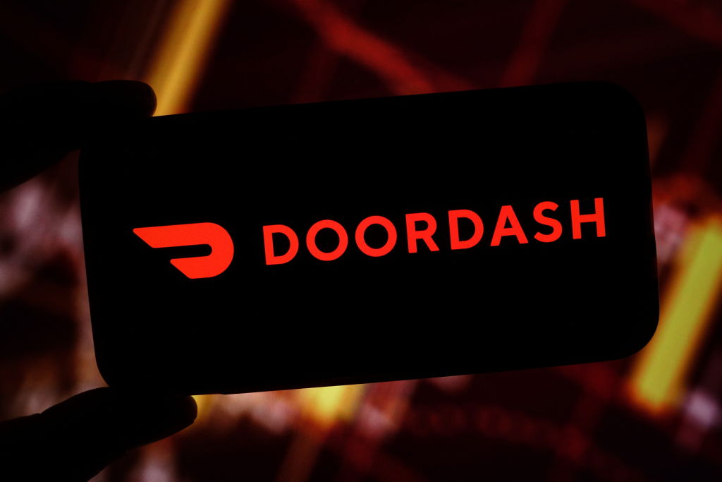 In this photo illustration, the DoorDash company logo is...