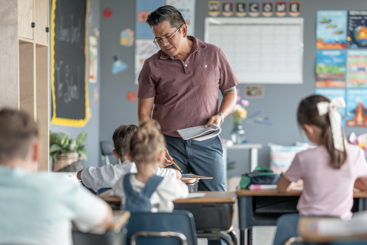 Teacher Helping Students in a Bright and Colorful Elementary School Classroom