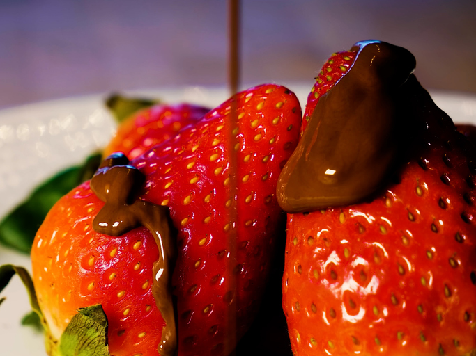 strawberries being drizzled with chocolate, close-up in motion